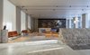 Modern home with Living Room, Chair, Sofa, Coffee Tables, Track Lighting, Pendant Lighting, and End Tables. During the renovation, Pawson and Gill added an entirely new building to the former hospital and convent. In the new structure, Pawson has created a modernist lobby, highlighting remnants of a 13th-century Crusader’s bastion wall that was uncovered during the excavation. Photo 2 of Jaffa Hotel