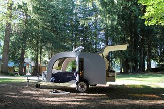The DROPLET has a kitchen at the rear which includes an acrylic, easy-to-clean countertop and backsplash; two LED lamps; a 12-volt slide-out fridge; a two-burner propane cooking stove; and drawers for storage. The sink is deep enough for dishes, and a closed-loop water system is hand-pump operated.