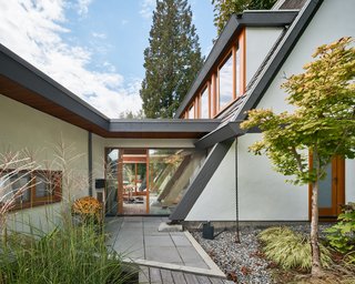 The addition is connected to the existing home by a glass "bridge" that serves as the entry and maintains visual continuity through to the backyard.