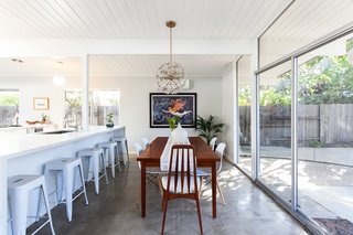 The dining nook sits between the kitchen island and a wall of glass. 