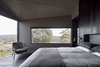 Modern home with Bedroom, Chair, Dark Hardwood Floor, Wall Lighting, and Bed. The bedroom also boasts a wall of sliding glass doors that open the home to its surroundings. Photo 6 of Oikos at Breakneck Gorge