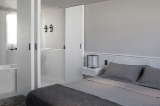 In the master suite, handcrafted, double-pivot doors in a brushed ash finish create an ensuite bathroom that can be fully opened up or closed off. Carrara marble molding outlines the room and provides an extravagant touch.