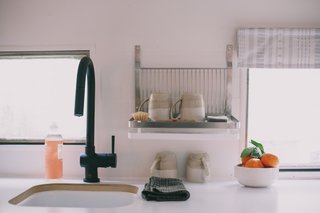 The minimalist kitchen features chic ceramics and a matte black faucet.