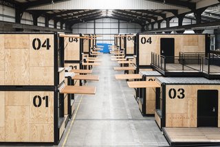 The mobile hotel rooms are made from repurposed shipping containers. Here they are shown stacked in a warehouse and ready to be deployed. 