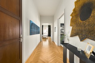 A hallway with herringbone floors leads to the living/dining area. 