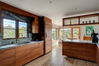 The kitchen was updated with mahogany cabinetry, including paneling on the refrigerator which matches the millwork. Marble countertops and backsplashes, paired with brass fixtures, add a luxe touch. 
