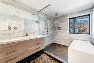 The en suite master bath features luxe marble-clad surfaces that include Carrera marble countertops and Piatra gray herringbone marble floors. There is also a deep soaking tub.