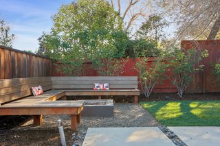 The backyard features custom built-in teak seating, a fire pit, and an organic vegetable garden.