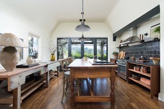 The kitchen features soapstone counters, a walnut island, handmade tiles, and an expansive door that leads to an covered, outdoor dining terrace.