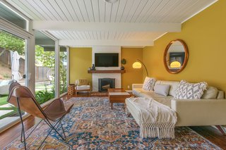 The living room has a wood-burning fireplace and a wall of windows with sliding glass doors leading to the backyard.