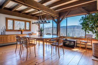 The dining room has an exposed beam ceiling and a row of nearly full-height windows.