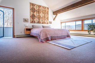 The master bedroom is located upstairs, and it has access to an outside terrace. A low row of windows runs the length of the wall.