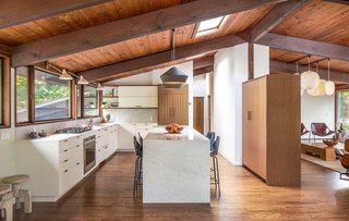 The elegant eat-in kitchen is one of the highlights of the renovation. It features a center island clad in Carrara marble, sleek custom cabinetry, and high-end appliances from Fisher & Paykel. There is also a skylight which floods the space with natural light.