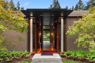 The grand entrance to the home features a full-height steel pivot door. 