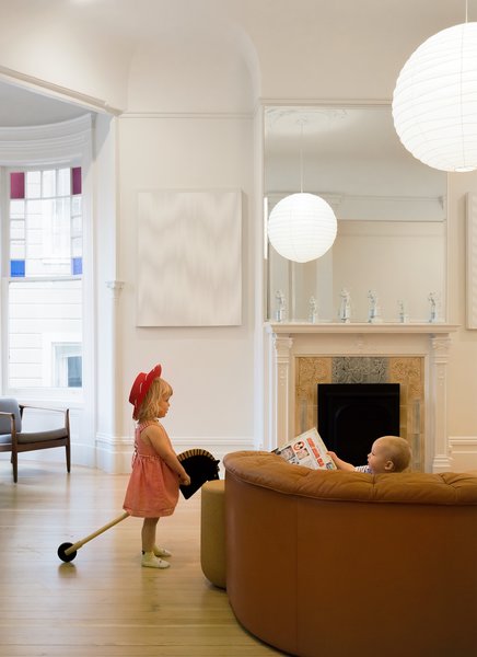 The Freeman children play in the living room, which features an elegantly carved fireplace.