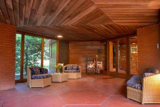 The exterior and indoor/outdoor spaces are a mix of brick and wood paneling. Hexagonal concrete floor tiles create continuity between interior and exterior.