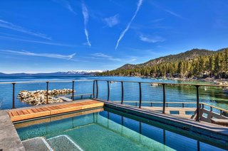 A pool on the deck overlooks the water and the surrounding landscape.  