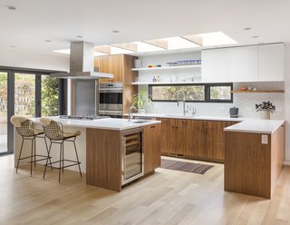 As a pastry chef who is also left-handed, Nicholas knew exactly how she wanted her kitchen renovation to play out so that it would best suit her own personal needs. She also wanted open shelving to display her collection of colorful dishes and ceramics. The walnut cabinetry was custom made by L&Z Specialties and topped with Caesarstone countertops. The kitchen island features Bertoia barstools, a SubZero wine cooler, and a Wolf gas cooktop. The flooring is white oak. Nicholas also has a Wolf double wall oven that meets her baking requirements. 