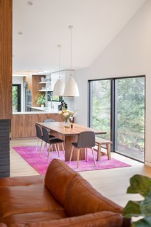 A peninsula with hidden storage serves as a divider between the kitchen and the dining room. Two Caravaggio Pendants by Fritz Hansen hangs over the dining table. The sectional sofa is a vintage find. 