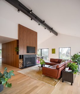 Another major focus of the renovation was vaulting the living room. "The main challenge that came up, which always comes up when we vault a living room with a fireplace, was that the fireplace's finished brick only went up to where the dropped ceiling was. Once the room was vaulted, we needed to find a creative way to resolve the finish transition. So we created a walnut-clad core that wraps around the fireplace—and around an existing mechanical room from the kitchen through the entryway, and into the dining room," explains Boyer. The insertion of wood also helps to tie the living space together visually. 
