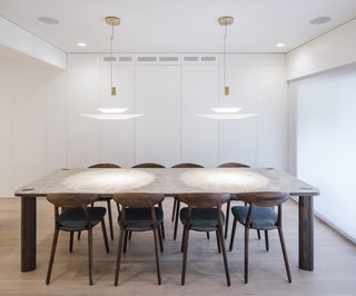 The dining room revolves around a bespoke dining table made of solid walnut and Emperador Light marble. The Wu dining chairs by Artisan feature Kvadrat upholstery; the delicate pendant lights are Flamingo by Vibia.