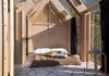 Modern home with Bedroom, Light Hardwood Floor, Night Stands, Rug Floor, and Bed. The chic, minimalist interiors sleep two and have a slightly rustic feel. There is only room for a double bed and a small stool. Photo 4 of Immerso Glamping Cabin