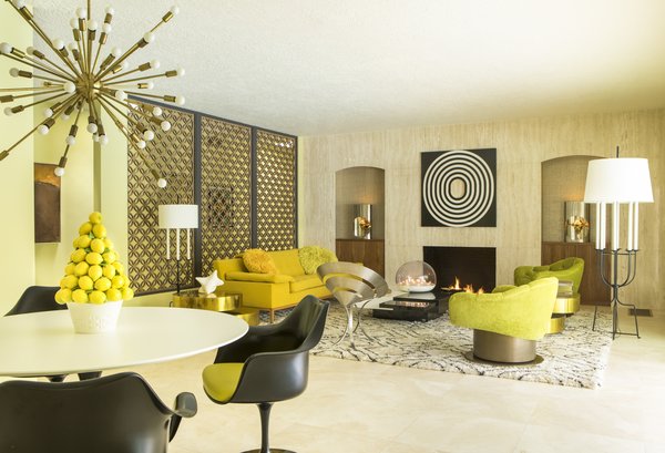 The three-bedroom, three-bath home opens to travertine flooring.  An aluminum grille divider echoes the ones on the facade, while built-in wood cabinetry fit the alcoves that frame the fireplace. 