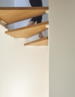The open-riser stairs reduce visual mass and allow light to filter down to the lower levels.