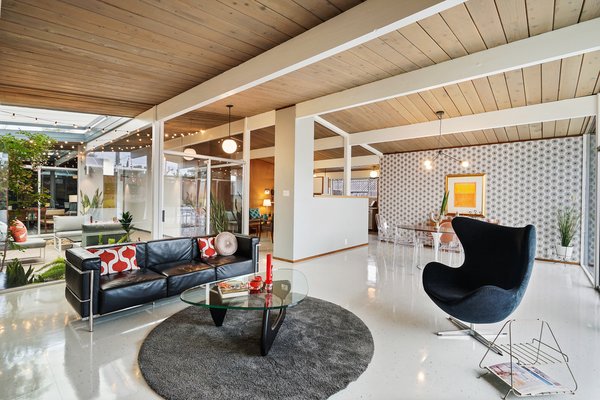 The open-plan living space is filled with natural light from the atrium and a full-height glass wall.