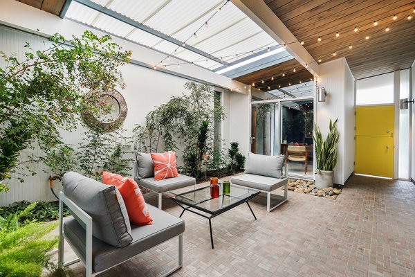 The lush glass-enclosed atrium greets you directly upon entering the home. A sliding roof shelters the space from the elements.