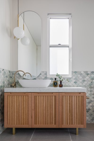 The Wall Of The Master Bathroom Is Tiled With Ming Green Marble Fan Tiles From Tera Nova Paired With Tumbled Limestone Floor Tiles From Tera Nova A Michael Anastassiades Flos Pendant Light From Living Edge Brightens The Space The Bespoke Vanity Was Design 