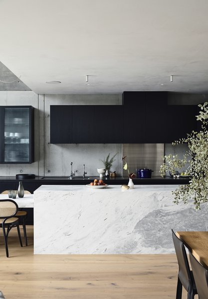 The sleek marble island pops against the black cabinetry—all of which was custom designed for the space. The rear countertop is made from black Zimbabwe granite. The flooring is oak timber in a custom 320 mm width.