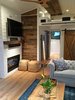 Modern home with Living Room, Two-Sided Fireplace, Gas Burning Fireplace, Track Lighting, Sofa, and Light Hardwood Floor. Living room and door to master bedroom, Chesterfield sofa, double-sided fireplace, reclaimed wood mantle piece, television, and reclaimed wood wall accent. Storage loft. Photo 10 of Iki Hau'oli Hale (Tiny Happy Home)