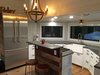 Modern home with Kitchen, Metal Backsplashe, Refrigerator, Cooktops, Range, Engineered Quartz Counter, Pendant Lighting, Drop In Sink, Light Hardwood Floor, Track Lighting, and White Cabinet. Full-size refrigerator and five burner chef's kitchen, 19' of quartz composite counter tops, bar seating area Photo 18 of Iki Hau'oli Hale (Tiny Happy Home)