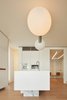 Modern home with Kitchen, Engineered Quartz Counter, Wall Oven, Microwave, Pendant Lighting, White Cabinet, and Medium Hardwood Floor. Casa Dolce Vita's brilliant white kitchen is a lesson in simplicity; Atelier Michael Hagara tucked all the appliances away neatly so certain features, like the pendant light, could shine. Photo 10 of Casa Dolce Vita