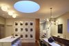 Modern home with Dining Room, Pendant Lighting, Chair, Table, Bar, Medium Hardwood Floor, Storage, Bench, Ceiling Lighting, Stools, and Recessed Lighting. This photo shows the changing color temperature of the drum skylight. Here at dusk when the light turns a beautiful blue. The photo also highlights our use of multiple styles of architectural lighting: tape-in recessed LED downlight, surface mounted and pendent fixtures combine to create a warm modern environment. Photo of White Street Residence