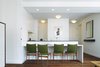An overall view of the kitchen & dining counter. Lighting alignments play a key role in our projects - here tape-in recessed lighting and surface mounted ceiling fixtures are centered on the kitchen and entry helping to frame a beautiful lithograph by the Belgian artist Pol Bury. Photo of Riverside Residence modern home