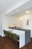 A three-quarter view of the kitchen and breakfast area. The lower seating area countertop is Glacier White Corian and the upper counter is Atlantic Bluestone. The chairs are vintage and reupholstered in Brushed Merino Sprig by Maharam. Photo 3 of Riverside Residence modern home