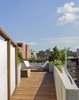 A view from the connecting ramp towards the upper level of the roof deck. A custom Portland cement stucco planter wall tapers in a wedge shape continuing the line of the building parapet. Military surplus canvas screens are on the right. These are removable allowing access to existing service areas on the roof. Photo 4 of East Village Roof Garden modern home