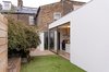 A timber-clad storage unit and seat in the courtyard is articulated as a small-scale sculptural volume of the same L-shaped geometry as the white-rendered kitchen building volume Photo 11 of Unité de Rénovation modern home