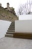 A concrete staircase connects the lower courtyard to the raised garden area, both framed by exterior walls and planters that extend the interior vocabulary into the exterior spaces. Photo of Periscope modern home