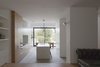 Modern home with Kitchen, Engineered Quartz Counter, Microwave, White Cabinet, and Porcelain Tile Floor. The spaces are further delineated by large, white sculptural volumes, which define soft edges between them while providing storage. The kitchen is articulated as a composition of smaller-scale volumes variously finished in stone, timber veneer, and white paint. Photo 2 of Vertical Intersect