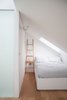 Modern home with Bedroom, Bed, and Medium Hardwood Floor. The top floor accommodates a glass-roofed shower, and a bedroom with its own small living space, top-lit by a motorized glazed roof and frameless roof-lights. Photo 10 of Vertical Intersect