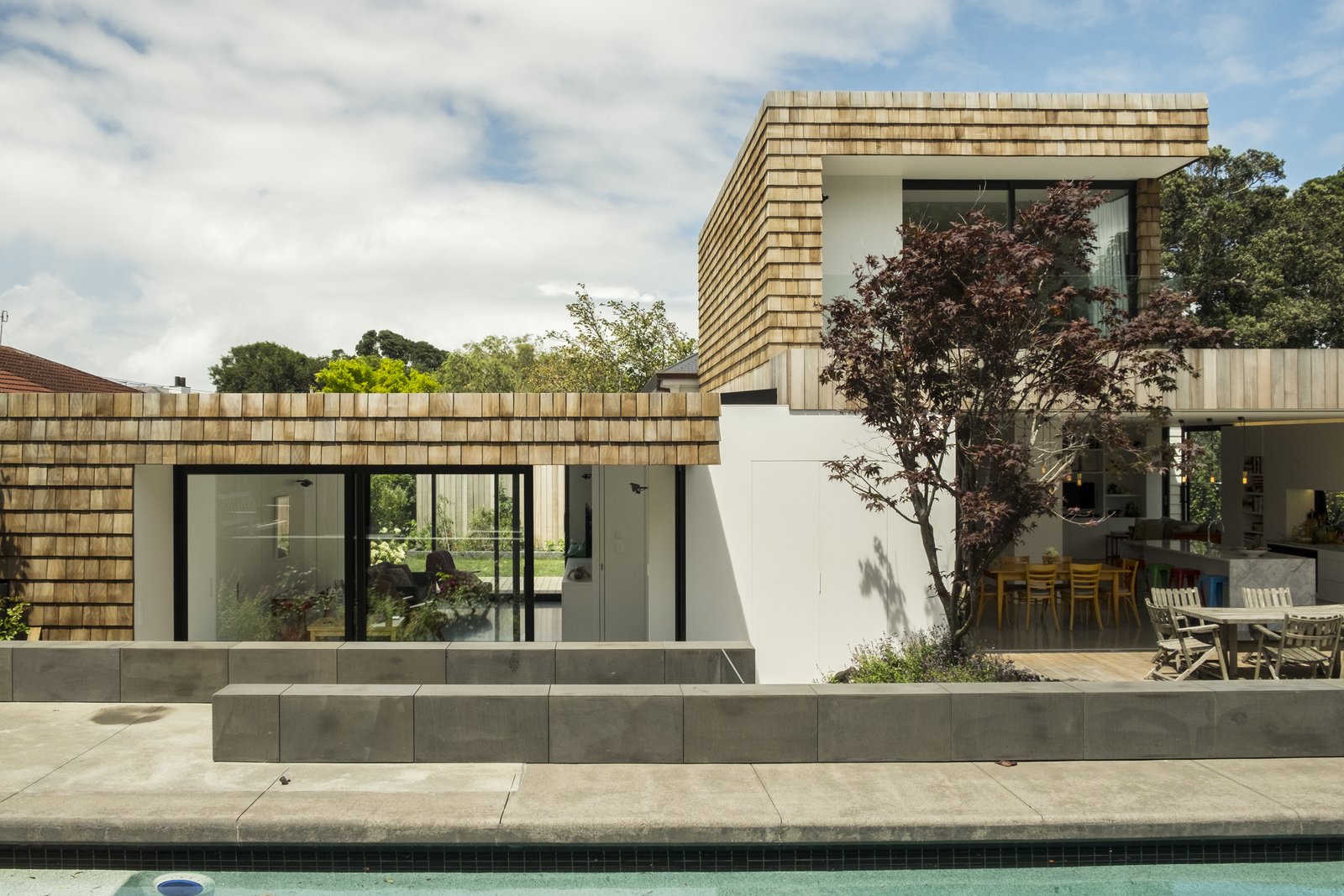 Viewed from the swimming pool, the new scheme largely obscures the original house—appearing as a new-build, modern house of a composition reminiscent of the mid-twentieth-century Case Study Houses.