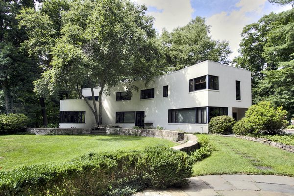 The low wall that lines the southern face of the house eventually curls around to surround a lily pool. The protruding dining room, seen at the far end, has ample windows to usher in views of the garden.