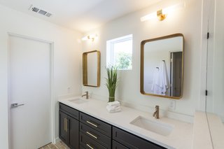 The master bathroom features brass mirrors, light fixtures, and hardware, taking visual cues from the brass accents found in the kitchen.