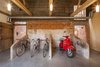 Modern home with Storage Room. The clients worked with Nossiter to preserve as many historical features as possible. The barn's cruciform plan arose from the model farm movement championed by original owner John Gurdon Esquire, who brought different farming functions under one roof. Here, what was once the old milking parlor now serves as bike and scooter storage. Photo 3 of Church Hill Barn