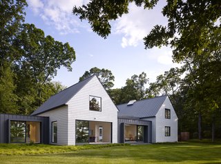 The simple form of each volume is a nod to regional architecture, while durable materials such as white cedar and zinc contribute to a low-maintenance vacation home. The windows and doors feature a bronze anodized aluminum finish on the exterior.