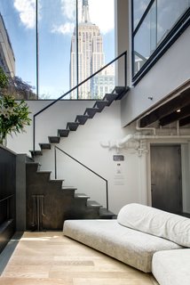 A blackened steel staircase by Delform leads to the upper level. A tall glass clerestory frames views of the Empire State Building and reinforces the indoor/outdoor motif