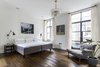 Modern home with Bedroom, Dark Hardwood Floor, Wall Lighting, Bed, Night Stands, Chair, and Pendant Lighting. Four bedrooms on the upper level feature wood floors, modern art, and ceiling beams, while the master bedroom on the third floor (pictured here) enjoys an ensuite bathroom and private terrace. On the rooftop, another bronze-clad terrace supplies a barbecue and city views. Photo 8 of Clerkenwell Cooperage